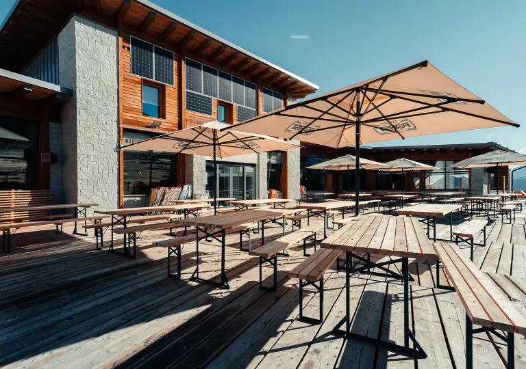 Outdoor patio with wooden tables and chairs under umbrellas