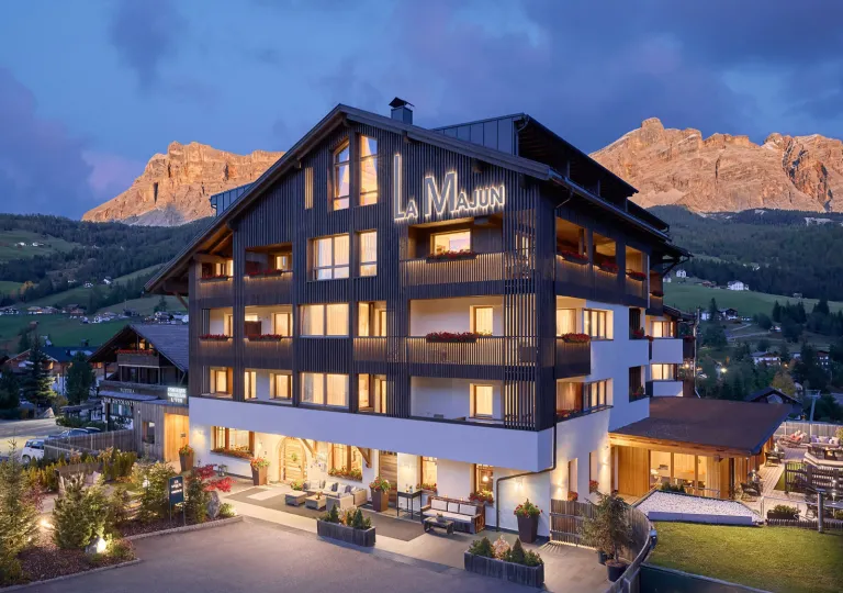 Exterior view of illuminated hotel building, with large mountains in the background