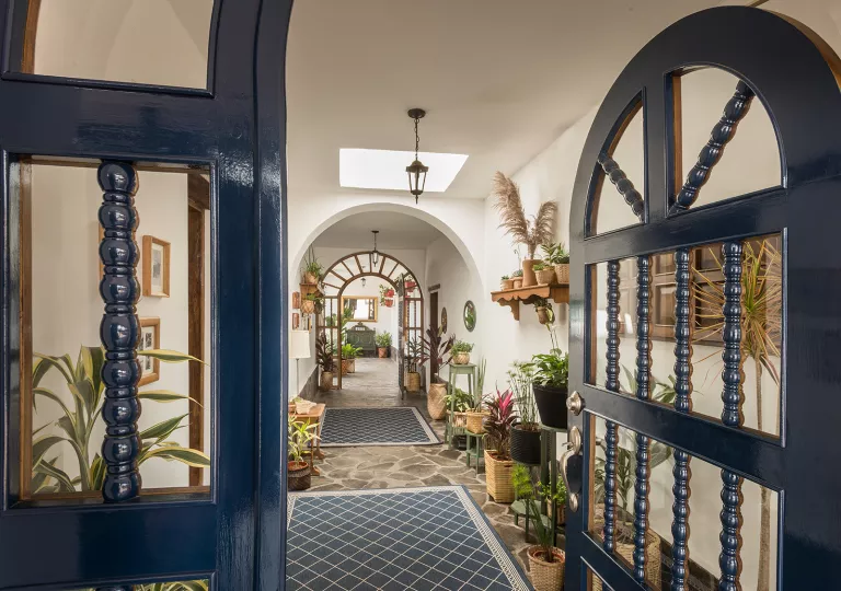 Entryway on a building with a long hallway full of plants and art pieces along the walls