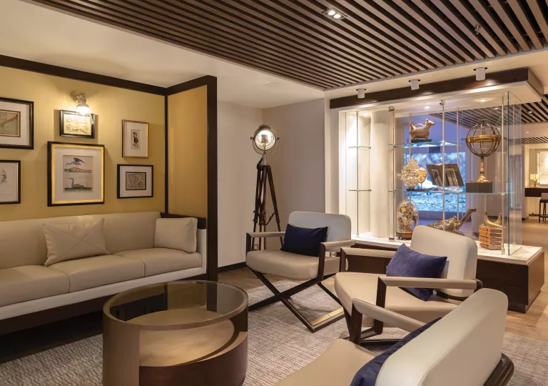 Room with beige couches and art pieces along the walls