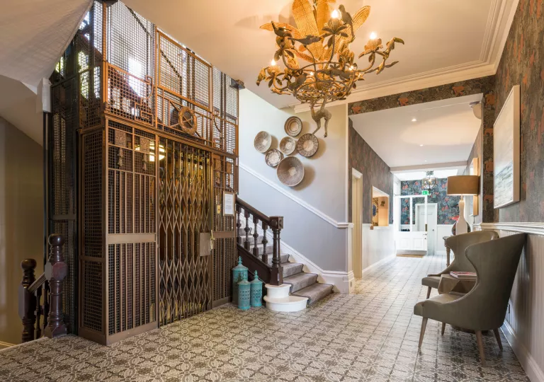 Hallway with a metal, exposed elevator and staircase to the left