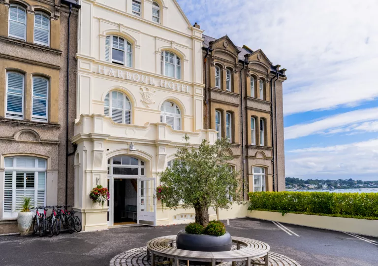 Exterior view of cream-colored building with an asphalt courtyard by the ocean