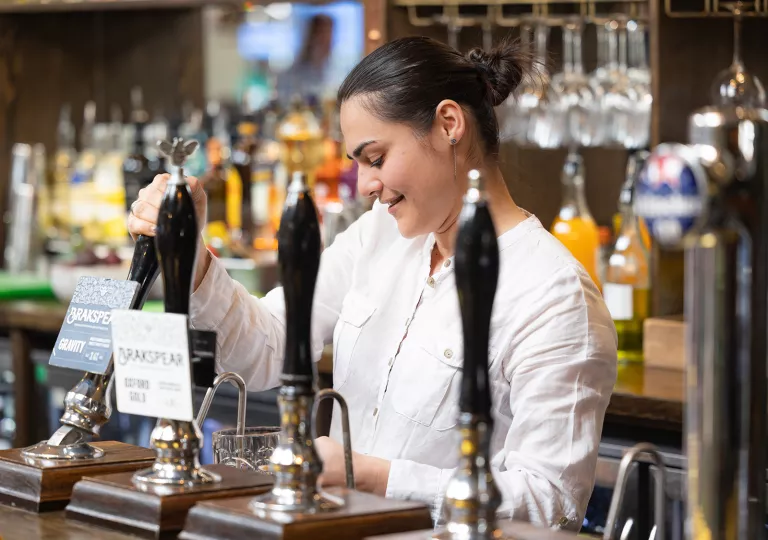 Bartender pouring a glass of beer while smiling