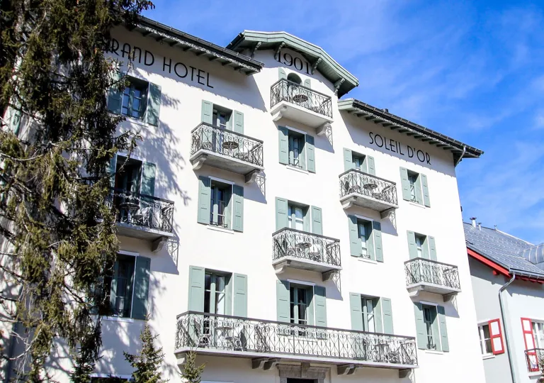 Exterior view of white hotel building with green window panes