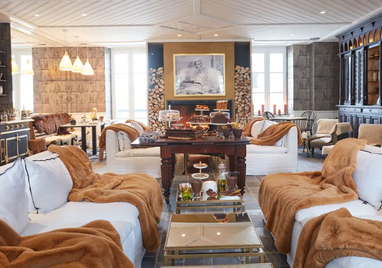 Seating area in front of a fireplace, with brown blankets on top of white couches