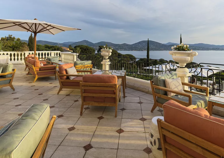 Outdoor patio with cushioned chairs, looking out to the ocean