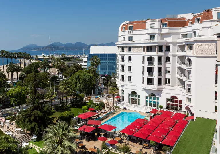 Exterior view of multi-story hotel building with an outdoor pool looking out to the ocean
