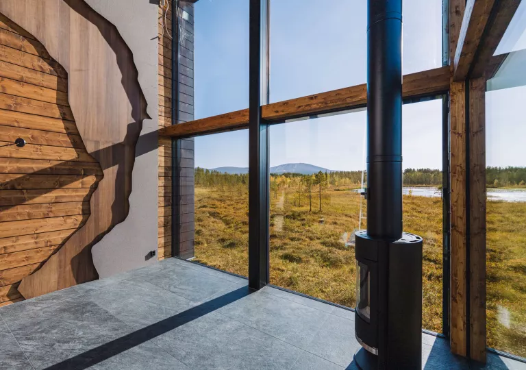 Corner of a large room with exposed wood walls and large windows