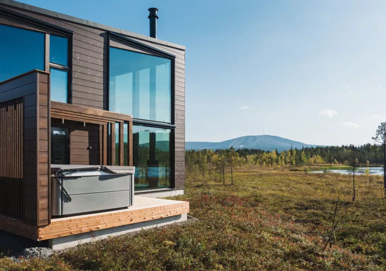 Exterior view of wooden building with large windows and a large valley in the back