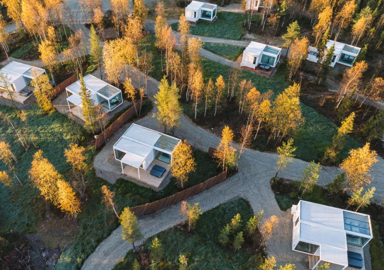 Sky view of white buildings in a valley with grass fields and yellow trees