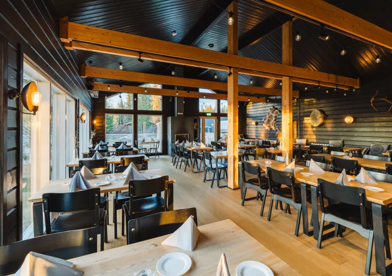 Indoor cabin-style room with dining tables and black chairs