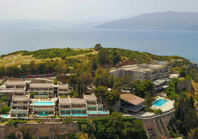Exterior, sky view of a large hotel complex on top of a hill, with mini outdoor pools