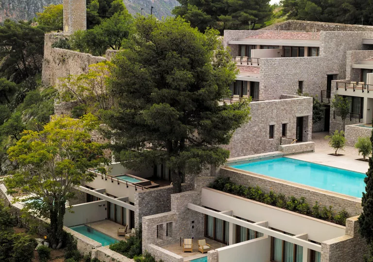Exterior view of stone hotel building with mini outdoor pools