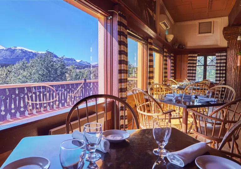 Dining hall with square tables next to large windows looking out to mountains