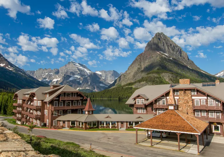 Exterior view of wooden cabin buildings in front of large lakes and mountains