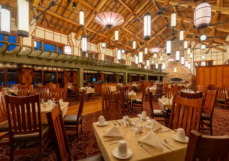 Large dining hall with skinny light fixtures and wooden chairs around each table