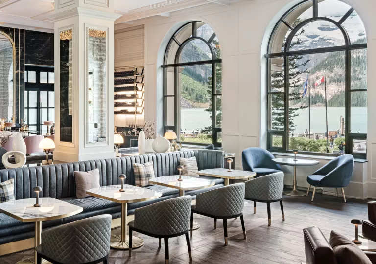 Hotel lounge with cushioned gray and blue chairs, with a bar in the back