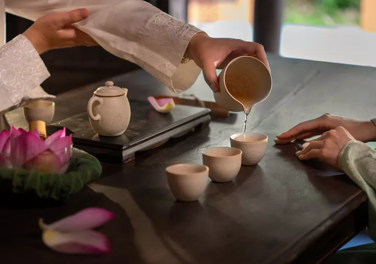 Person pouring tea into three tea cups