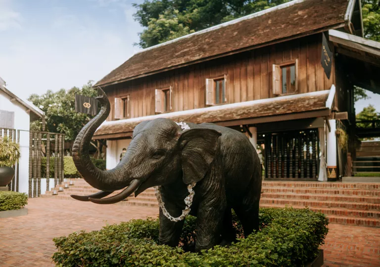 Exterior view of brown house with a bronze elephant statue in front