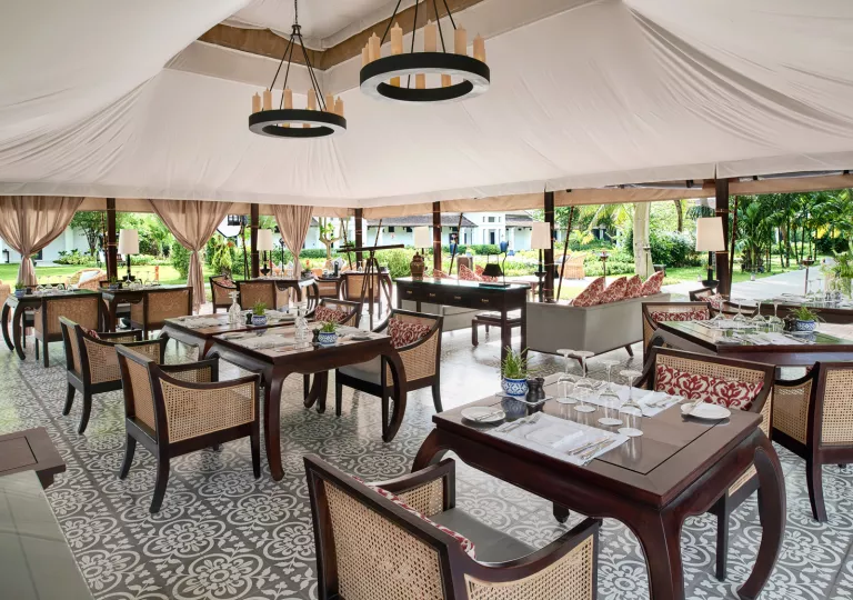 Outdoor dining area with large tent covering leading to a forest in the back