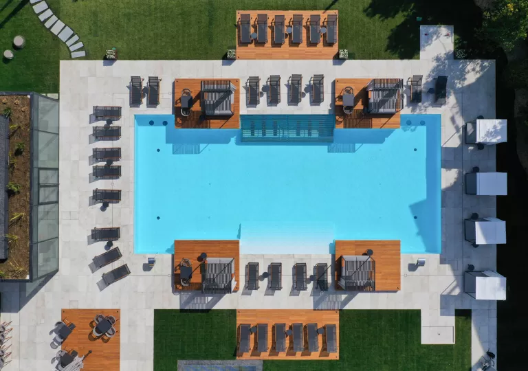 Sky view of an outdoor pool, surrounded by black chairs and wooden platforms