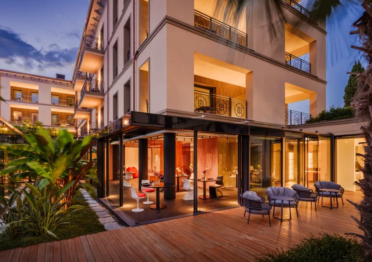 Exterior, nighttime view of hotel buildings with cushioned chairs
