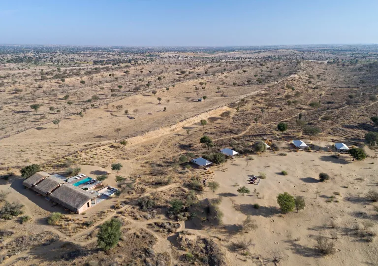 Sky view of a large desert valley with a house to the left