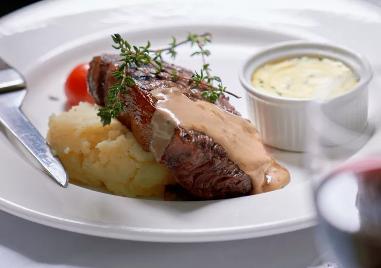Plate of grilled steak and mashed potatoes, with a brown sauce on top