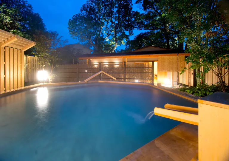Outdoor sauna and open bath, surrounded by tall trees