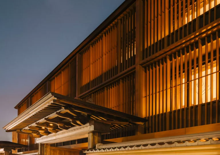Exterior view of wooden temple building with illuminated rooms inside
