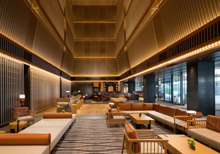 Hotel lobby interior with wooden tables and beige couches