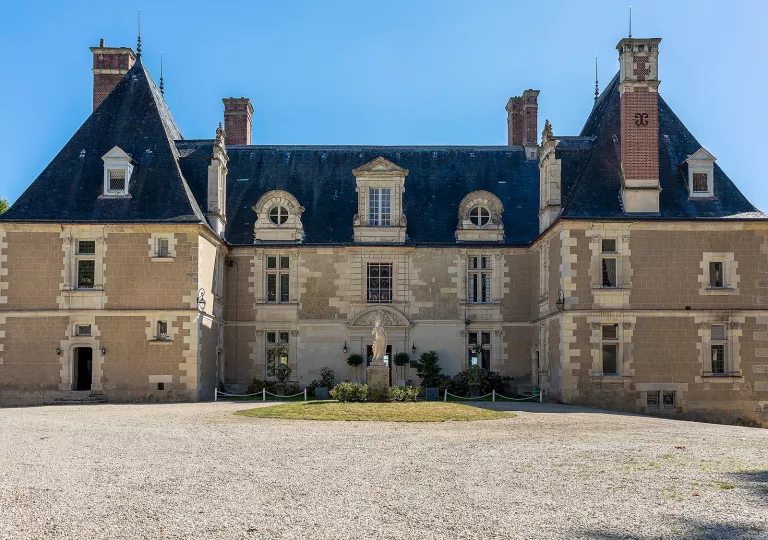 Exterior view of stone building with a gravel courtyard