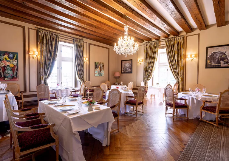Indoor dining hall with a chandelier and tables with white tablecloths