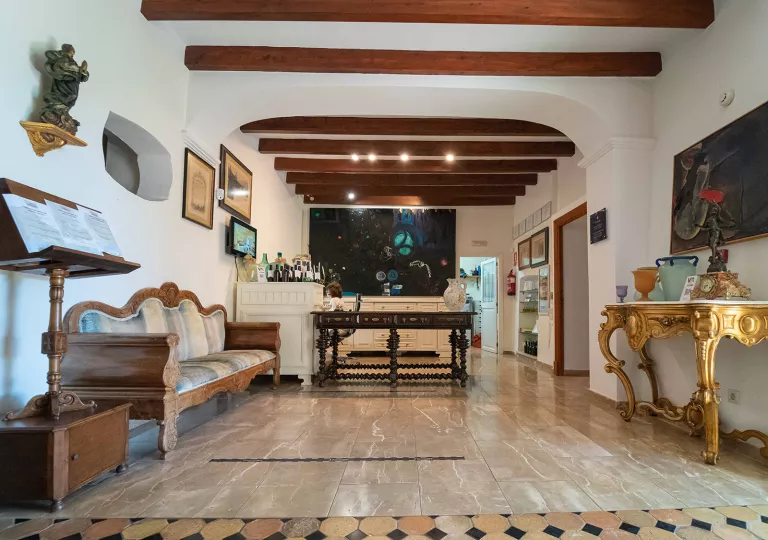 Indoor foyer and seating area with wooden furniture and paintings on the wall