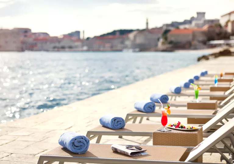 Row of reclining pool chairs on a dock in front of the ocean