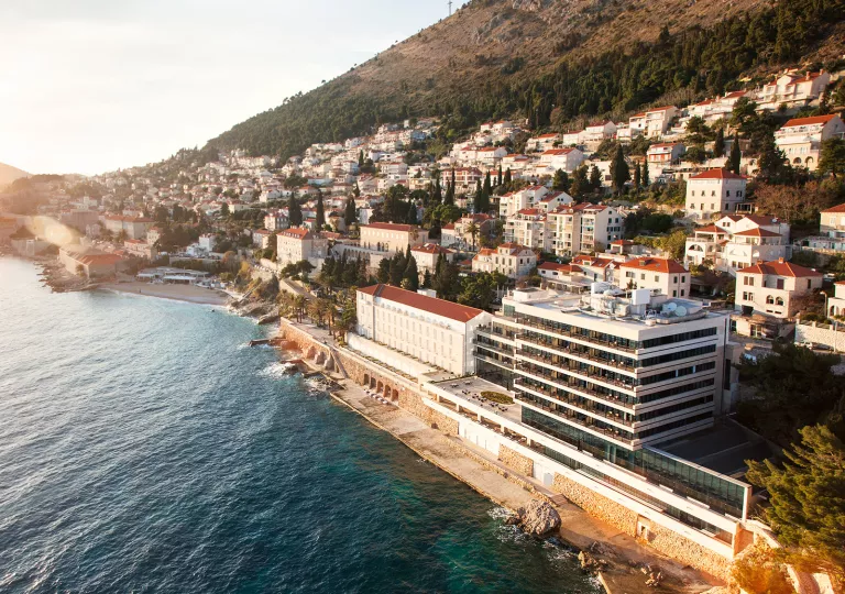 Sky view of a town of white and red buildings with the ocean to the left