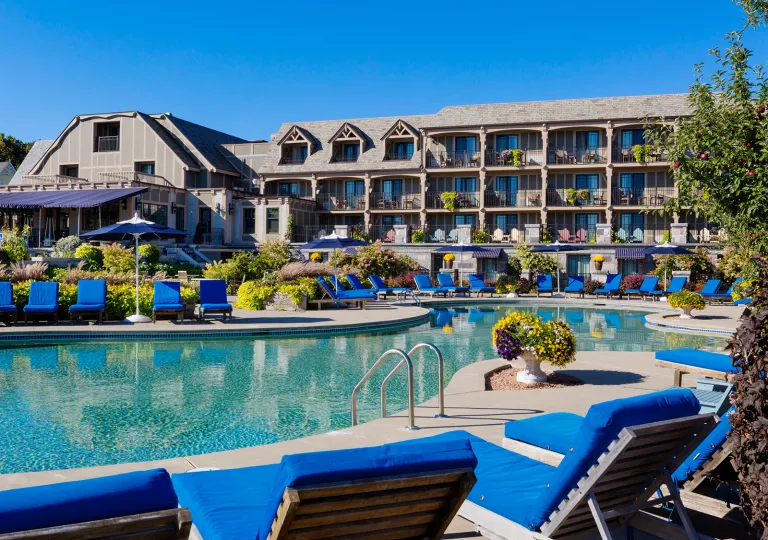 Outdoor pool surrounded by blue reclining chairs, and a hotel building in the background