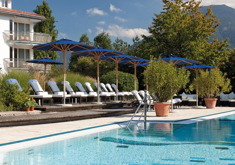 Outdoor pool with white pool chairs and blue umbrellas