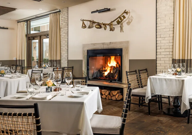 Restaurant dining hall with white dining tables and a fireplace