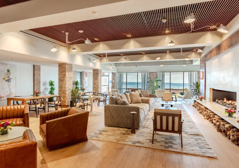 Lounge and seating area in front of a large fireplace and large windows in the back