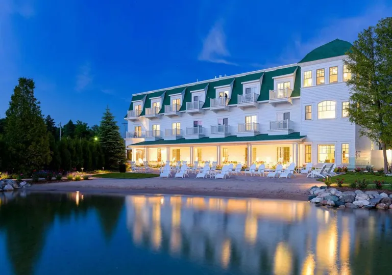 Exterior view of white and green hotel building with the beach in front