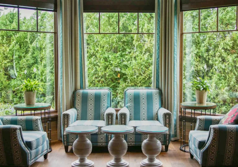 Room with large windows and green and white chairs along the walls