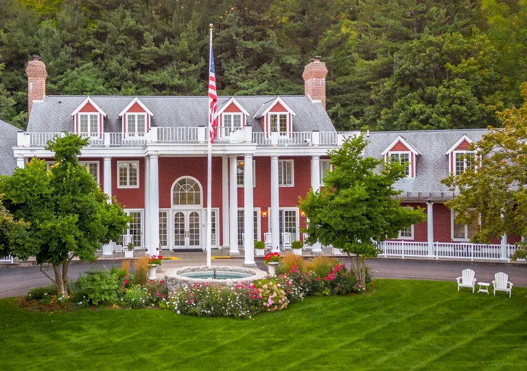 Exterior view of red and white building with an American flag and grass field in front