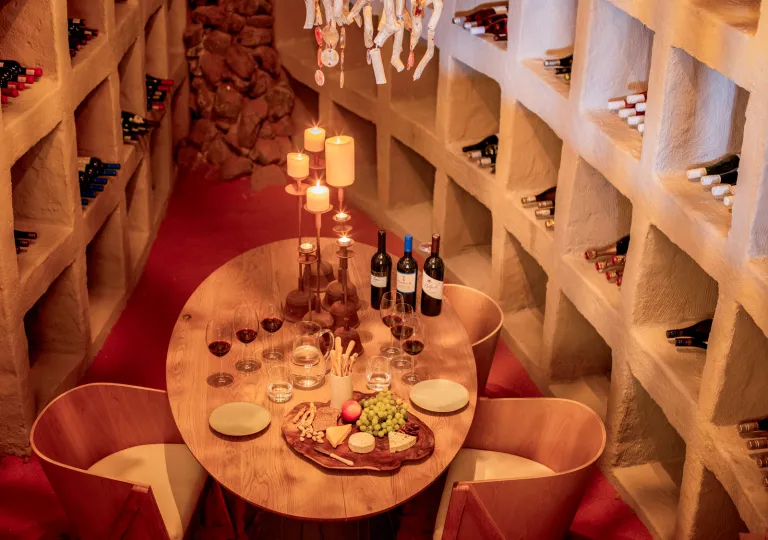 Wine cellar with a table and two chairs, and shelves full of wines surrounding