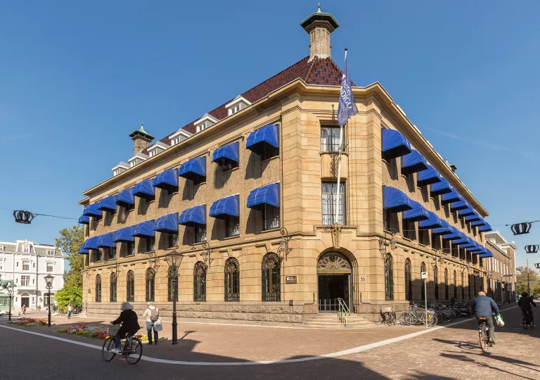 Exterior view of of stone, 2 story building with blue coverings over the windows