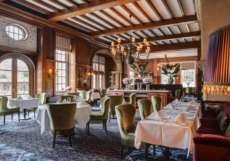 Dining area with green cushioned chairs and white table cloths on dining tables