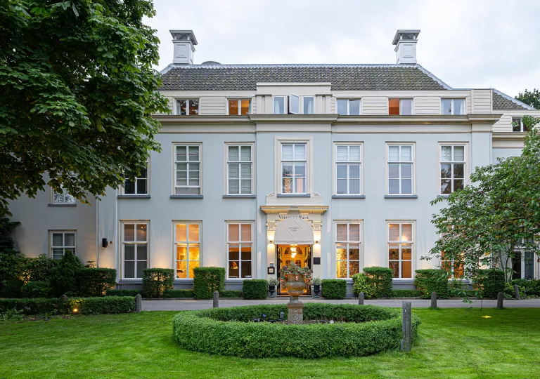 Exterior view of white two-story building with a grass field in front