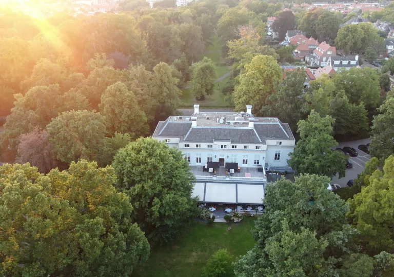 Exterior, sky view of white building surrounded by tall trees