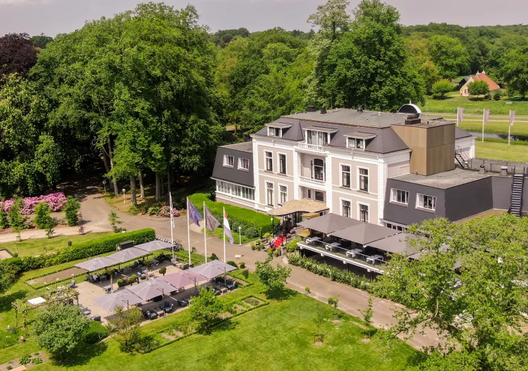 Exterior, sky view of beige and gray hotel building with a garden and patio in front