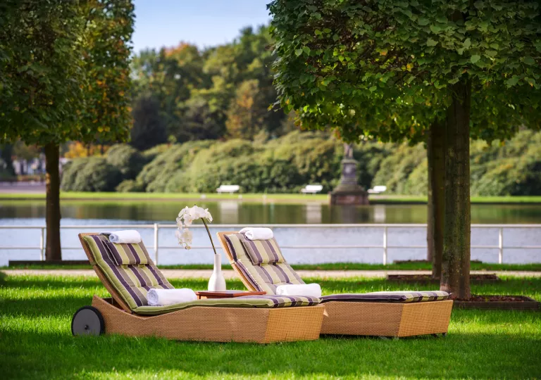 Two reclining chairs on a field of grass, with a lake in the background
